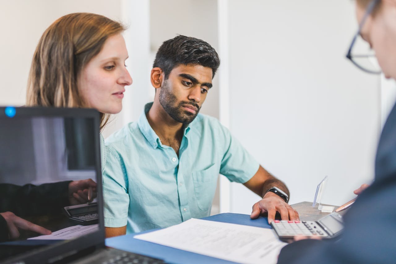 A young couple in discussion with a real estate agent in a modern office setting.